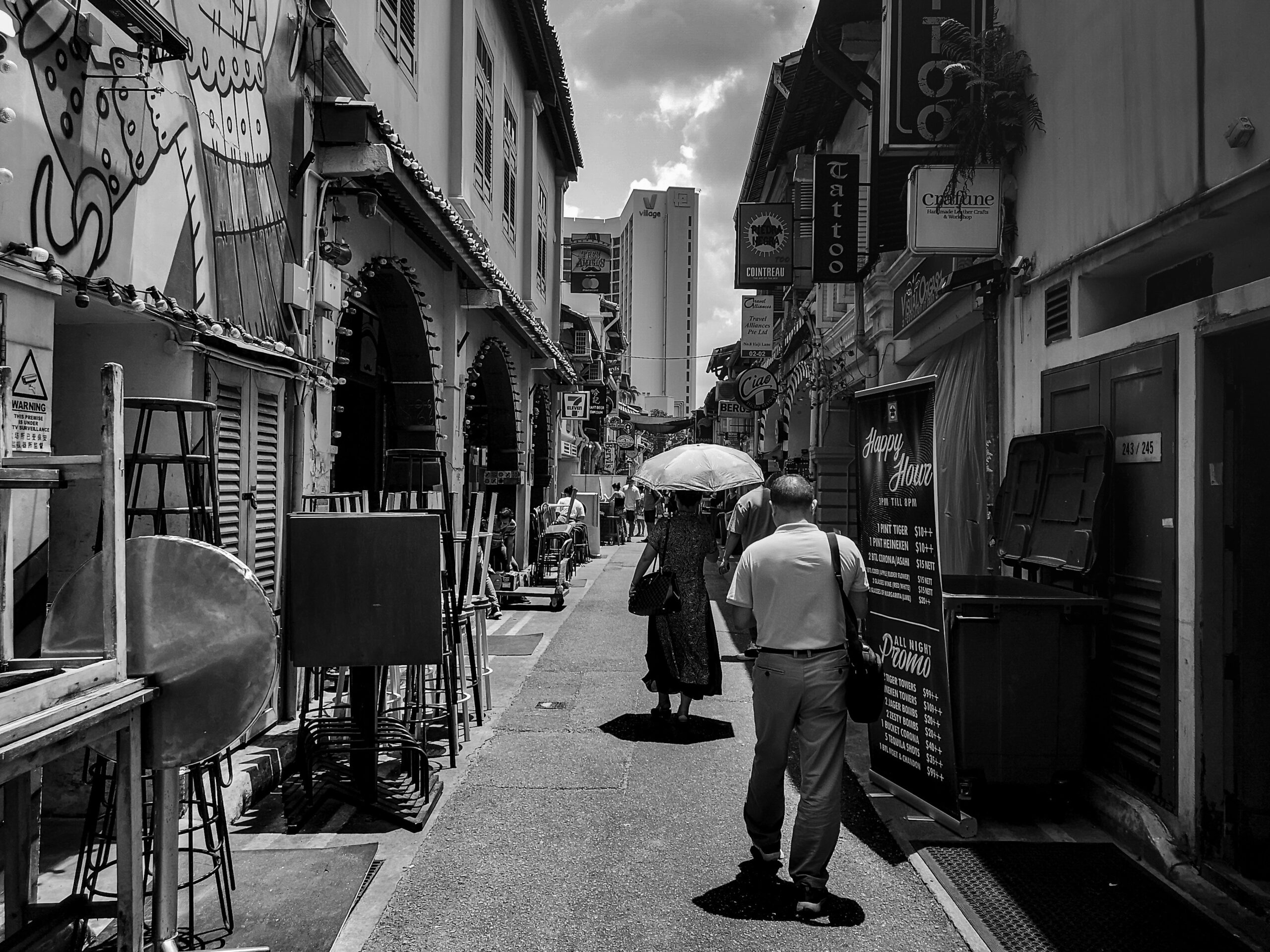 grayscale photography of man and woman walking along narrow pathway